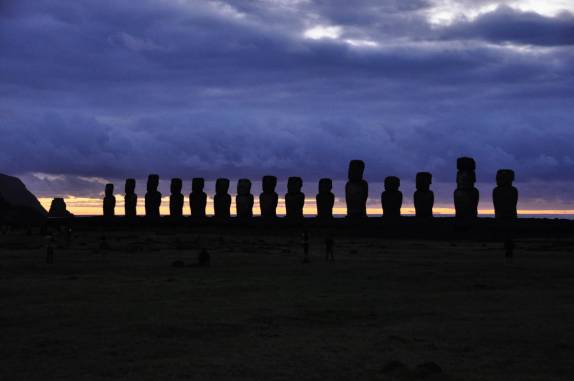 Turistas assitem ao nascer-do-sol atrás da fileira de Moais de Tongariki, no sul da Ilha de Páscoa, ilha chilena no meio do Oceano Pacífico